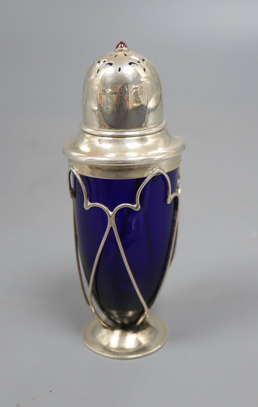 An Edwardian Arts and Crafts silver and gem set mounted blue glass sugar shaker, no makers mark, 12.3cm.